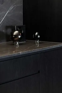 Modern kitchen with black cabinets and marble countertop.