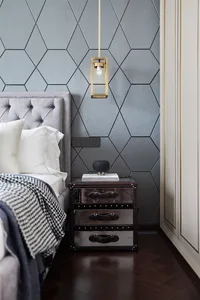 Modern grey bedroom featuring a upholstered headboard and metallic nightstand.