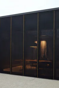 A modern industrial office with black metallic screens and warm lighting.