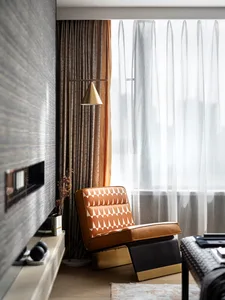 Modern interior design featuring a patterned couch, floor lamp, and fabric curtains in a living room.