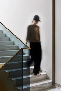 A modern staircase with marble steps and a glass railing leads upwards.
