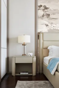 A minimalist bedroom with a large bed, nightstand, and lamp, featuring modern materials and a serene atmosphere.