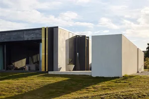 Modern residential house with a concrete exterior and large glass windows.
