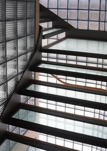 An industrial-style staircase with glass blocks and metal railings.