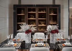 Modern dining room with black marble table, glass vases, and white chairs