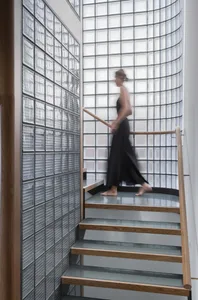 A modern interior with wooden and glass stairs leading up to a curved glass wall.