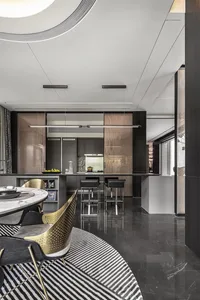 A modern kitchen with black marble countertops, metallic accents, and a black and white striped rug.