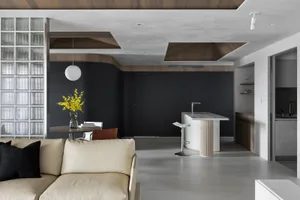 A modern living room with a glass window, wooden furniture, and a concrete floor.