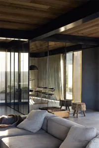 Industrial-style living room with grey sofa, wooden stools, and glass windows.