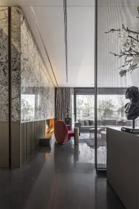 A modern living room featuring marble walls, a glass fireplace, and metallic accents.