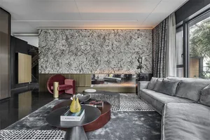 A modern living room with a marble wall and a gray sofa with a patterned rug and round tables.