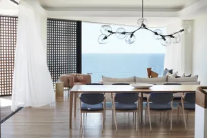 Modern, minimalist living room featuring a spacious open concept layout, with a large dining table and comfortable seating ar