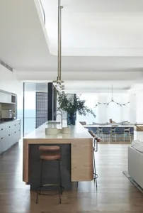 Modern residential kitchen with white marble tile flooring, wooden island, and pendant lighting.