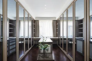 A modern wardrobe with glass doors and dark wooden flooring, featuring sleek lines and minimal design.