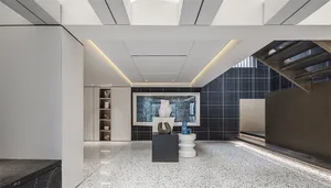 A minimalist lobby featuring black-and-white tiled flooring and a terrazzo table with sculptures and art.