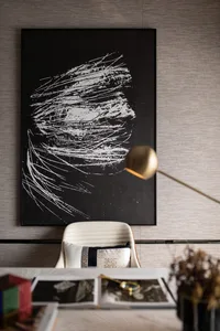 A modern office setting with a minimalist design, featuring a white collaborative space with a black abstract artwork, a whit