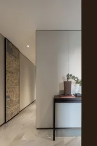 A modern minimalist interior design featuring a sleek, white wall with a large, abstract painting and a black console table w
