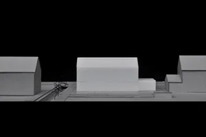 A layout model constructed from cardboard, depicting architectural design elements in a minimalist black and white setting.