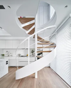 A modern, minimalist kitchen featuring a spiral staircase with white metal railings and wooden steps, designed with sleek, fu