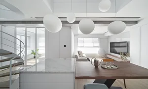 A modern apartment featuring a marble kitchen island and a living room with concrete walls and canvas seating.