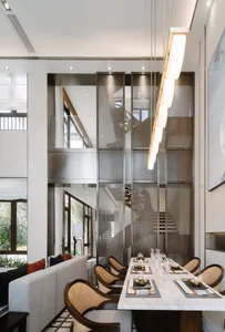 Modern dining room with glass walls, wooden chairs, and white marble table.