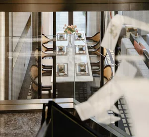 A modern dining room with a glass table and wooden chairs.