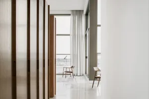 A modern interior white corridor with wooden doors and a view through a large window.