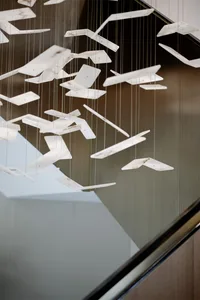 A modern lighting installation featuring aluminum panels hanging from the ceiling in a contemporary interior setting.