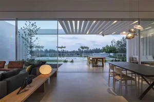 Contemporary living and dining room featuring concrete floors and large glass windows.