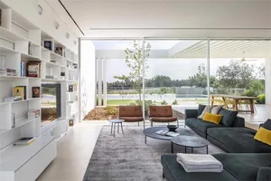 A modern living room featuring glass walls, canvas seating, and cement flooring.