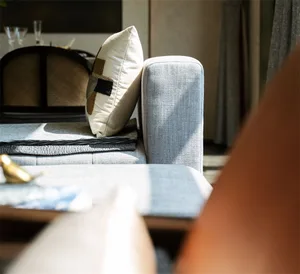 Modern living room featuring a gray couch with a decorative cushion and a stack of blankets.