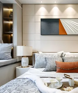 A minimalist bedroom featuring a bed with marble and fabric textures, complemented by a marble lamp and a wall-mounted abstra