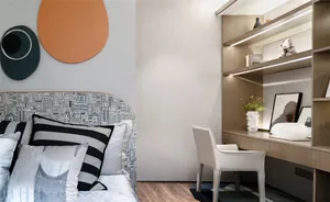 A modern residential bedroom featuring a bed with beige upholstered headboard and matching pillows, accompanied by a minimali