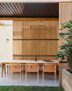 A modern industrial outdoor space featuring wood furniture and a slatted wooden wall.