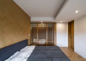 A minimalist bedroom with bamboo laminate flooring and a textured wall.