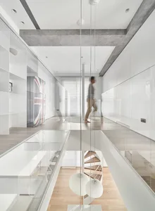 A minimalist interior space featuring white walls, concrete columns, and wooden flooring.