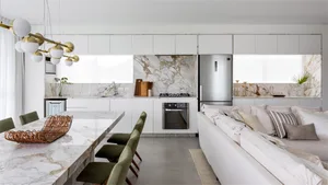 A minimalist kitchen with marble countertops and white cabinets.