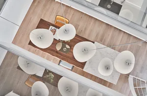 A modern dining room featuring a wooden table with a marble top, surrounded by chairs and pendant lights above.