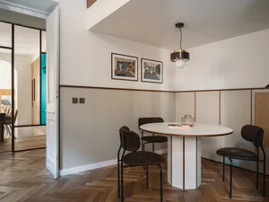 Modern dining room with wooden flooring, glass table, and metal chairs.