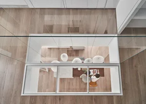 A modern kitchen with glass walls and a wooden floor