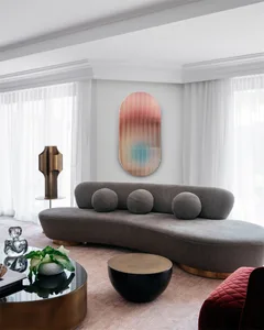 A modern living room with a曲面沙发, round brass tables, and a brass lamp.