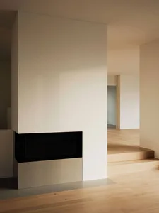A minimalist modern interior design with white plaster walls and wooden flooring.