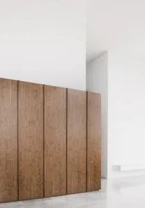 A minimalist interior featuring wooden cabinets against a white wall.