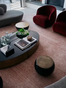 Contemporary living room featuring a sleek black oval coffee table with metallic accents, surrounded by stylish red and gray