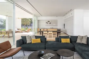 A modern living room featuring a dark green sectional sofa adorned with mustard yellow accent pillows, set against a minimali