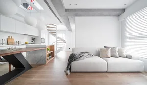 A contemporary, minimalist living room featuring a white sofa, wood flooring, and modern lighting.