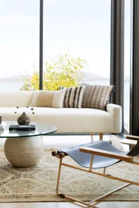 Modern living room featuring a white couch with soft, plush cushions, a glass coffee table, and a sleek, black lounge chair o