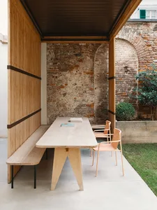 Outdoor dining area with wooden furniture and brick wall background.