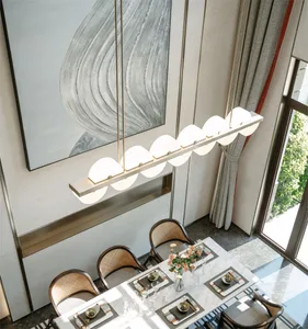 A modern residential dining room featuring a marble table, plush chairs, and elegant lighting.