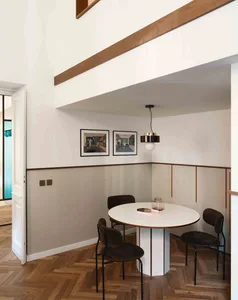 A modern dining room with a round table, chairs, and artwork on the wall.